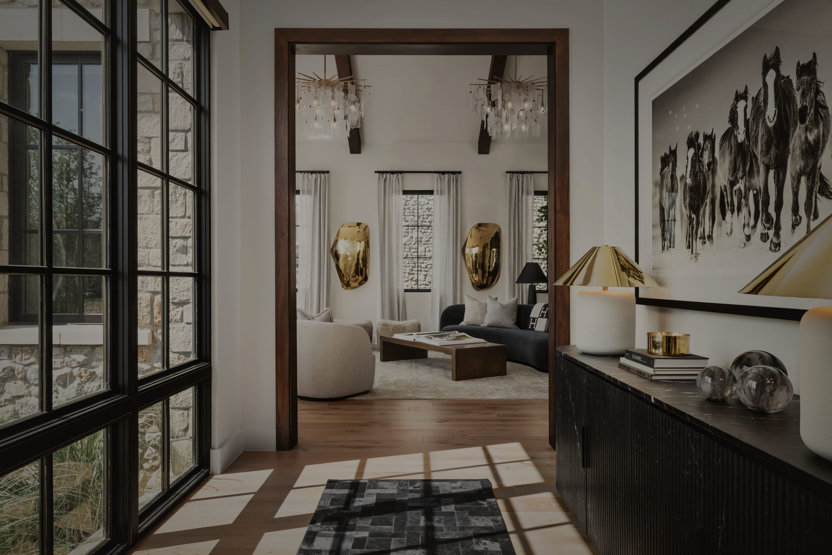 Entry hall with black steel windows, a horse print above a black console and sunlight across the floor