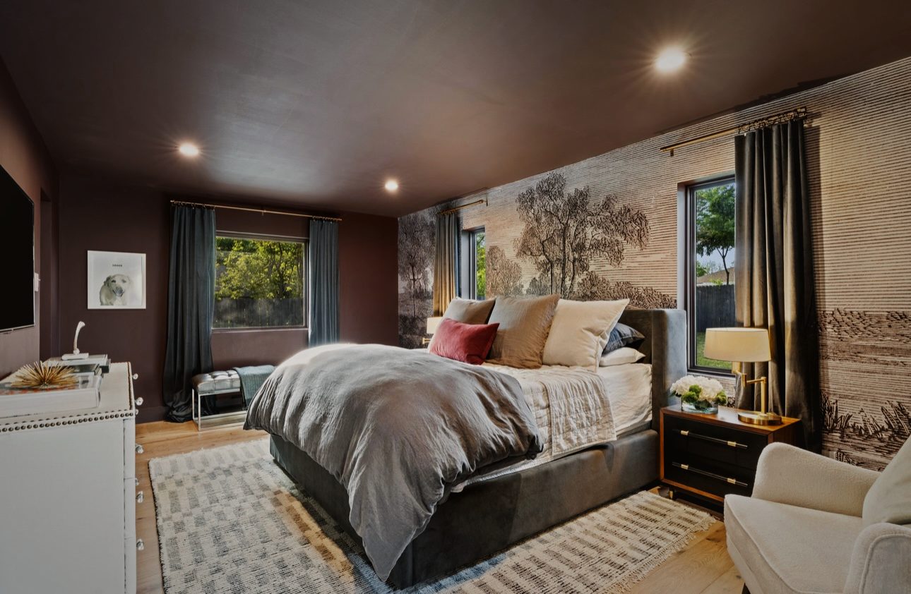 Primary bedroom with a landscape mural, a gray upholstered bed, dark walls and black nightstands