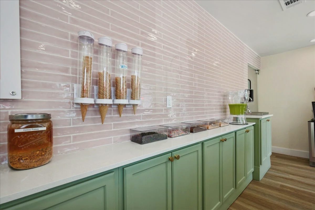 Cone dispensers on a pink tile wall over a sage green counter