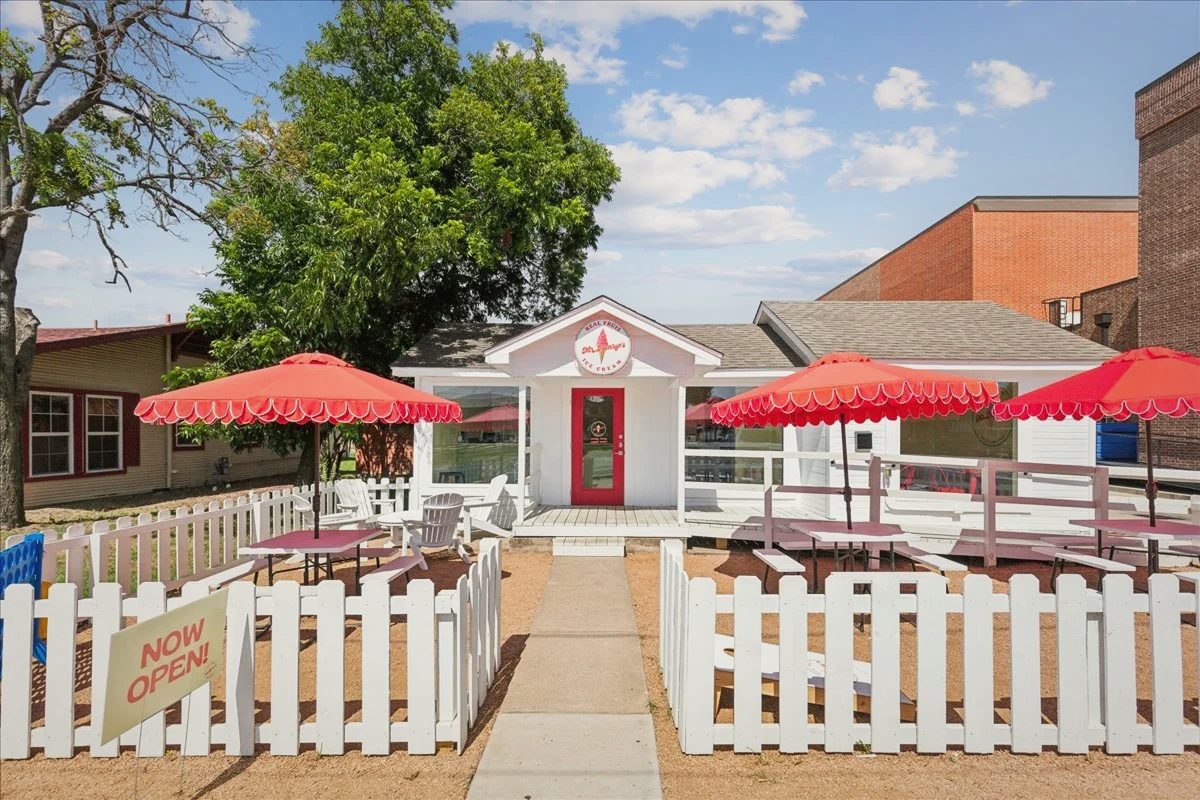 Mr. Henry's from the street: a small white building with a red door, a white picket fence and red umbrellas