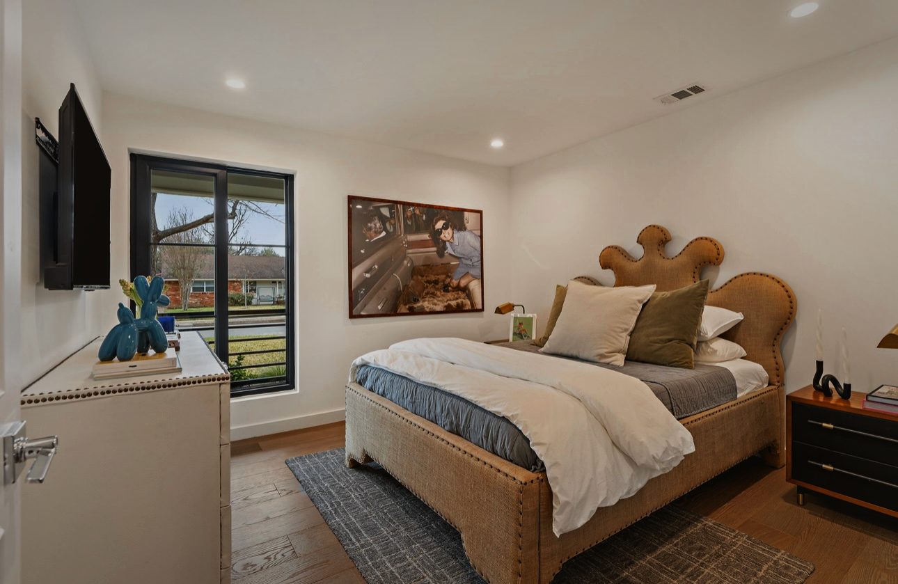 Bedroom with a scalloped upholstered bed, a black window and a framed print above a black nightstand