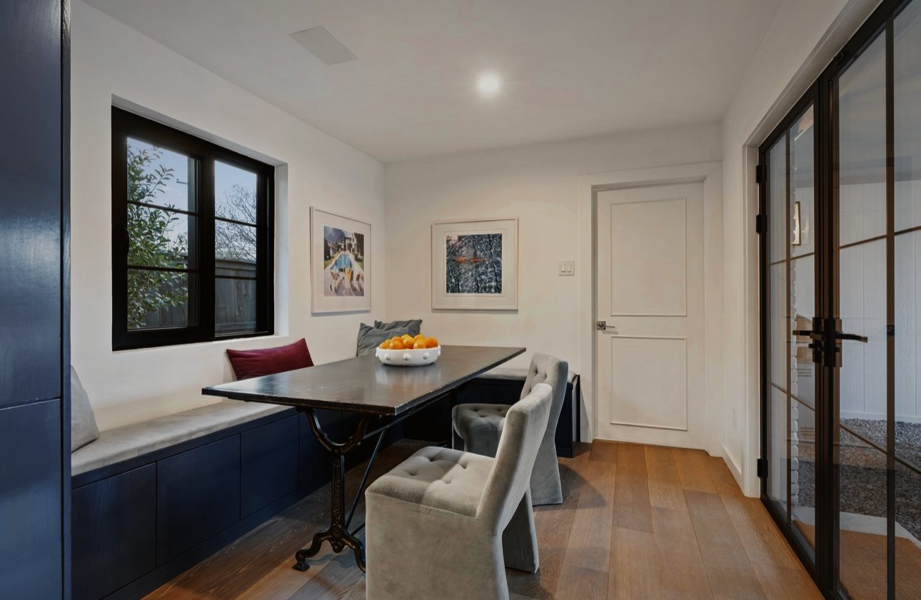 Breakfast nook with a navy banquette under a black window, a dark table and gray upholstered chairs