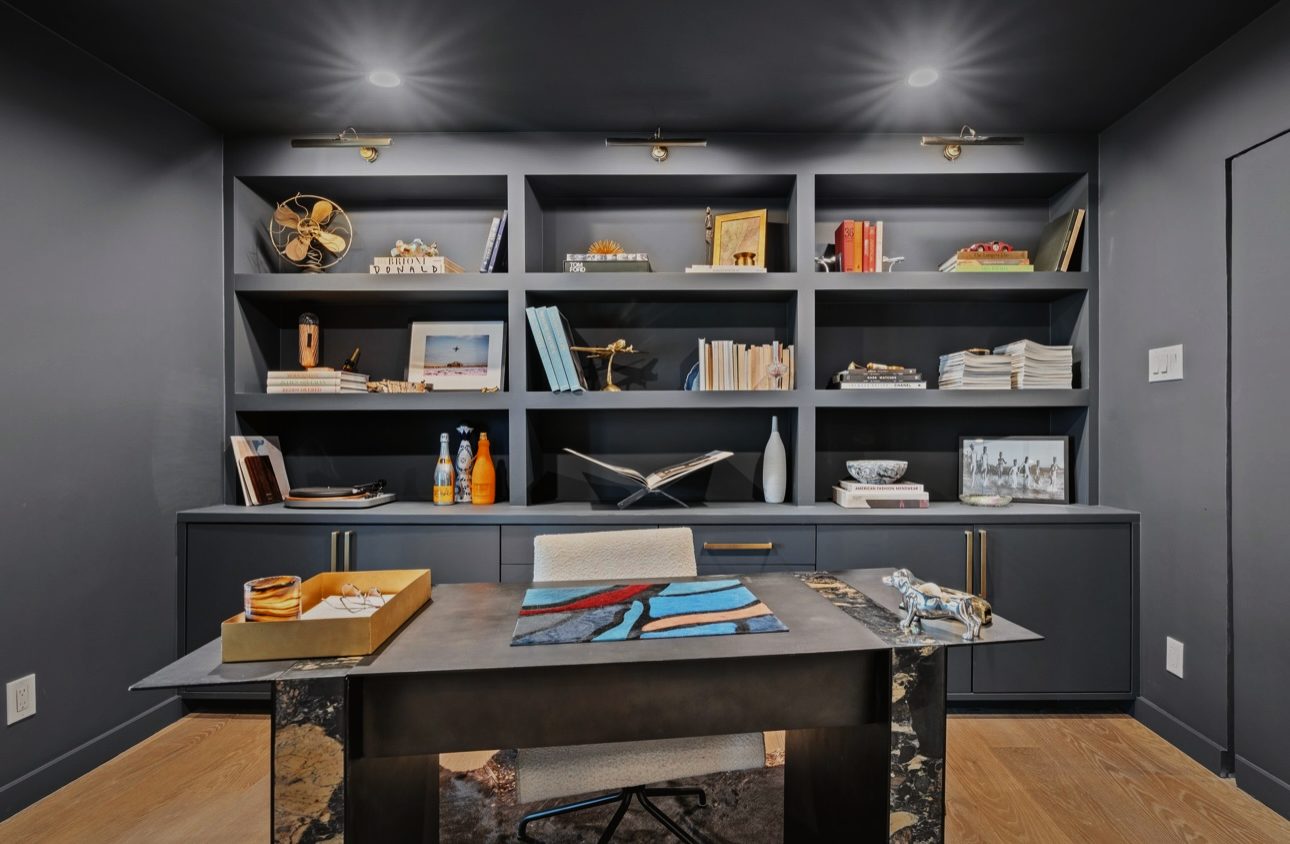 Office in deep charcoal with built-in shelves, picture lights and a black stone desk