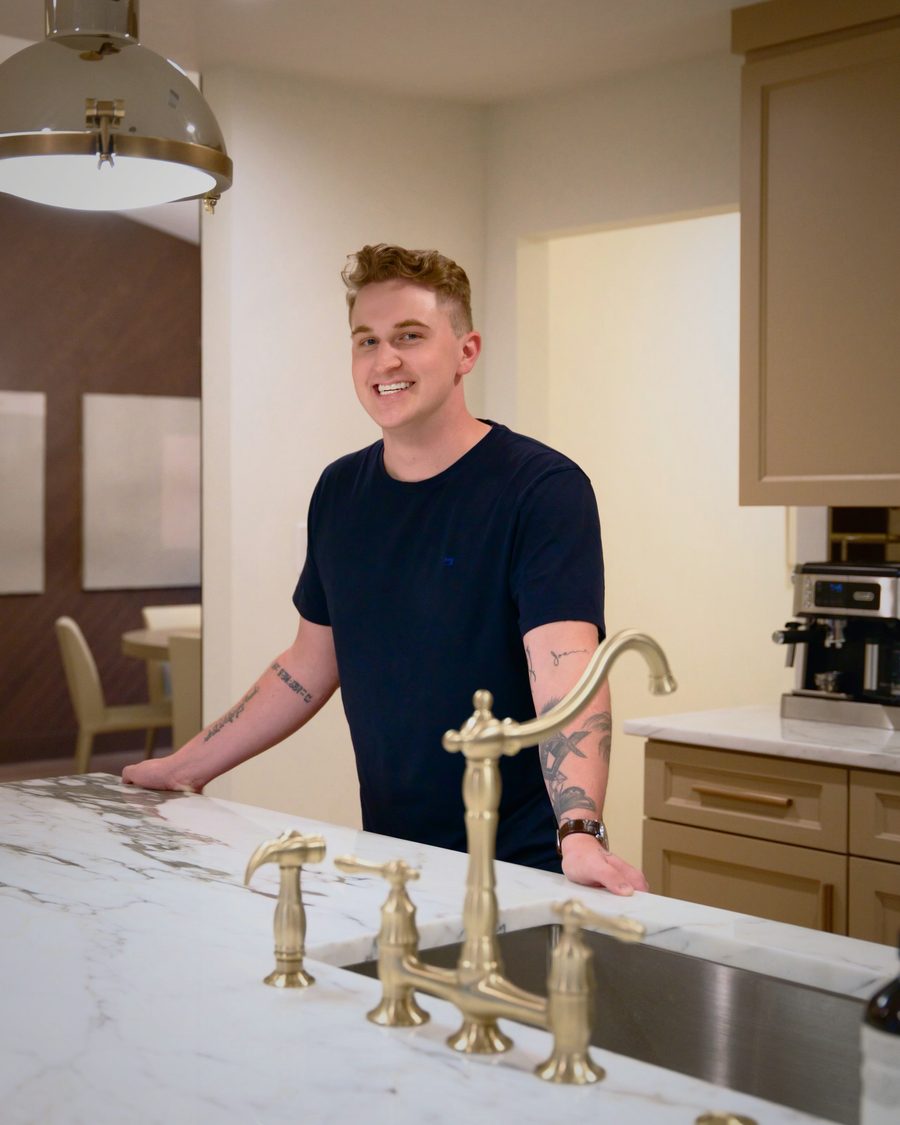 Spenser Marriot standing at a marble kitchen island with a brass bridge faucet